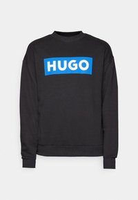 Sweat-shirt noir à manches longues avec poignets et ourlet côtelés, avec un logo rectangulaire bleu avec le texte blanc "HUGO" sur la poitrine.