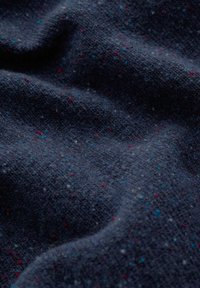 Texturerat marinblått tyg med ett prickigt mönster av röda och blå fibrer, som visar upp en mjuk, vävd struktur och subtil djup.