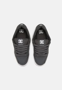 Chaussures de sport grises avec tige synthétique lisse et accents en maille, dotées de lacets gris, d'une pointe perforée et d'un logo sur la languette.