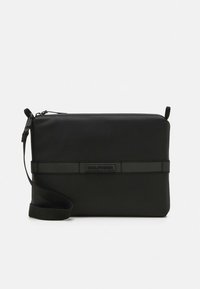 Mustast sünteetilisest materjalist ristkere koti lame kujuga, tõmblukuga, reguleeritava rihmaga ja horisontaalse rõhuasetusega ribaga, millel on brändi logo.