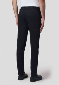 Czarne spodnie o prostym kroju, z zapięciem na guzik w tylnej kieszeni oraz szlufkami na pasek. Materiał wydaje się gładki i wszechstronny.