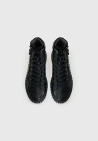 Chaussures hautes en cuir noir avec lacets, surface texturée, fermeture éclair sur le côté et semelles en caoutchouc présentant un motif de profil distinct.