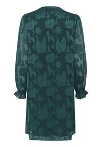 Turkos genomskinlig klänning med blommig broderi, långa puffärmar och volangärmar. Har en rund halsringning och en lös, flödande silhuett.