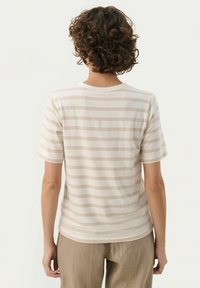 Short-sleeve striped t-shirt in soft beige and cream cotton. Features a crew neck and relaxed fit, with horizontal stripes across the back.