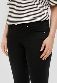 Zwarte denim jeans met een slim-fit ontwerp, voorzien van voorzakken en zilverkleurige hardware. Gecombineerd met een gestreepte korte mouwen top.