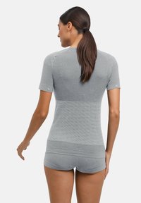 Szara koszula z krótkim rękawem o dopasowanym kroju i fakturowanym wzorze na ramionach i górnej części pleców. Materiał jest gładki i elastyczny.
