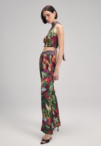 Tvådelad outfit som består av en kort topp och vida byxor. Tyget är färgglatt med blommönster i gröna, burgundy och orange nyanser.