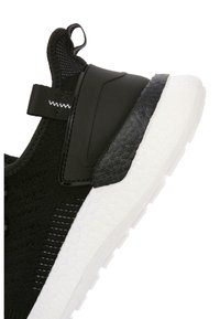 Czarne sneakersy z teksturowanym cholewką w plecionkę, solidnymi czarnymi akcentami i białą podeszwą z heksagonalnym wzorem. Pętelka na pięcie ułatwiająca zakładanie.