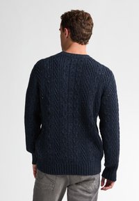 Pulover tricotat de culoare albastru marin, cu un design texturat în cablu, manșete și tiv cu nervuri, și un guler clasic de tip crew.