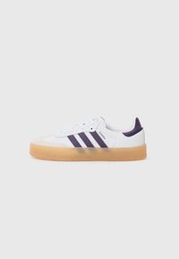 White sneakers with purple stripes, a gum rubber sole, and suede toe cap. Features lace-up design and "Samba" branding on the side.