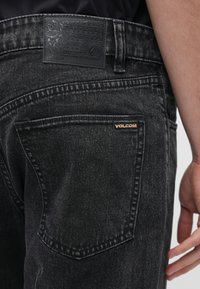 Τα μαύρα τζιν από τζιν ύφασμα διαθέτουν υφή, αντίθετη ραφή και ετικέτα με το λογότυπο της Volcom στην πίσω τσέπη.