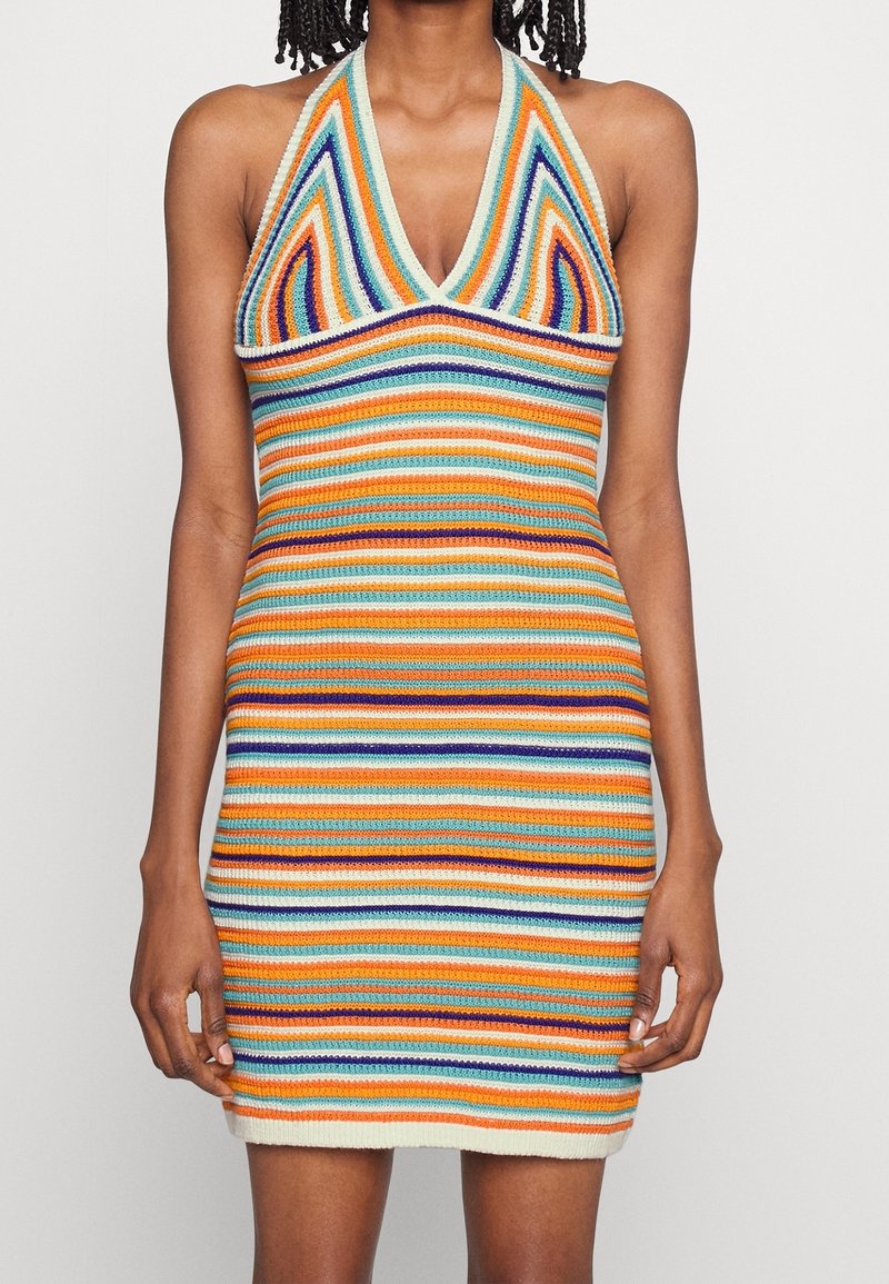 Femme portant une robe sans manches en maille rayée multicolore avec un décolleté en V et une silhouette ajustée.