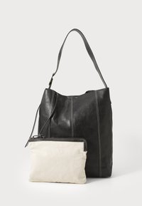 Svart lær tote bag med fremtredende sømmer og en enkelt skulderstropp. Inkluderer en beige lerretspose med glidelås.