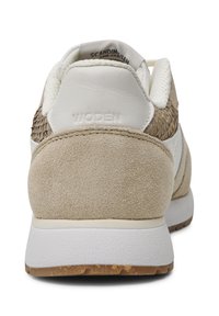 Sneaker beige con un motivo intreCCIato testurizzato sul tallone, morbida pelle scamosciata, dettagli bianchi e una suola in gomma con battistrada marrone chiaro.