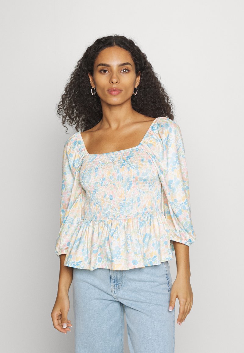 Blusa peplum floral em cores pastel, com decote quadrado, corpete franzido e mangas bufantes. Feita de um tecido leve.