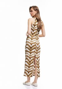 Ärmelloses Kleid in Braun und Weiß mit Muster und seitlichem Schlitz. Hergestellt aus glattem Stoff, zeichnet sich durch eine taillierte Silhouette und einen knielangen Schnitt aus.