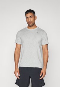 T-shirt grigia Nike realizzata in tessuto leggero, con maniche corte, scollatura rotonda e logo nero sul lato sinistro del petto.
