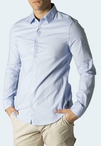 Camicia button-up azzurra in misto cotone, con colletto classico, maniche lunghe e un logo discreto vicino alla tasca sul petto.