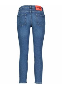 Jeans azules ajustados con una textura suave, que cuentan con bolsillos traseros y una cinturilla con logo rojo. El denim tiene un acabado de lavado clásico.