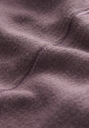 Lila tyg med en mjuk, texturerad yta och subtila nyansvariationer. Synlig sömnad ger detaljer längs kanterna.