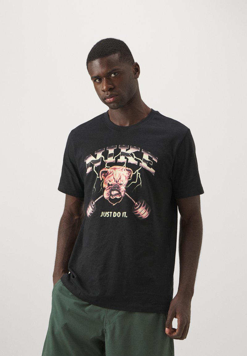 Sort bomulds T-shirt med grafik af en bulldog, der løfter vægte, prydet med teksten "NIKE" og "JUST DO IT" i livlige farver. Korte ærmer.