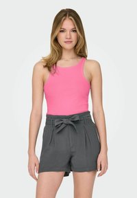 Top rosa de tirantes combinado con pantalones cortos grises de cintura alta que presentan un detalle de lazo y dos bolsillos laterales. Textura de tela suave.