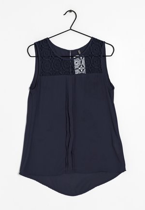 Marineblauwe mouwloze blouse met kantdetails bij de hals, geplooide voorkant en een gebogen zoom. Gemaakt van lichtgewicht, gladde stof.