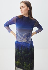 Abito a maniche lunghe con stampa di paesaggio montano in tonalità di blu e verde, con un colletto alto e maniche trasparenti. Texture morbida.