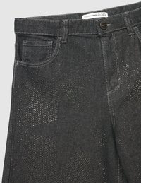 Czarne dżinsy z przodu kieszeniami, szlufkami na pasek i zapięciem na guzik, z subtelnymi, błyszczącymi łatkami na tkaninie.