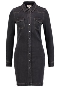 Musta farkkutunika pitkähihaisilla, kärjellä varustetulla kauluksella ja kahdella rintataskulla. Ominaisuuksiin kuuluu edessä napitettava sulku ja vaaleat ommelkoristukset.