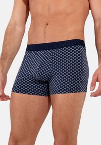 Boxer da uomo di colore blu navy con un motivo geometrico a rombi in tonalità più chiare. Vita elastica morbida, design aderente e lunghezza fino a metà coscia.