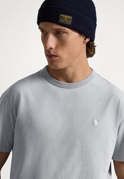 Ljusgrå bomullst-shirt med ribbad textur och rund halsringning. Har en liten vit logotyp på vänster bröst och kompletteras med en marinblå stickad mössa.