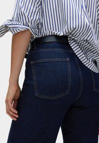 Tmavě modré džíny s přiléhavým střihem, s klasickým pětipocket designem a kontrastními oranžovými švy.
