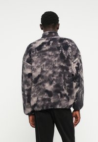 Α�διευκρίνιστη, oversized ζακέτα σε γκρι και μαύρο tie-dye σχέδιο. Διαθέτει όρθιο γιακά και σκιαστούς ώμους, με μαλακή, υφή φινιρίσματος.