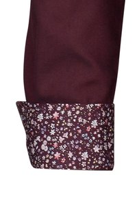 Polsino di camicia bordeaux con un motivo floreale nei colori rosa, bianco e blu. Il polsino presenta un design floreale contrastante su uno sfondo uniforme.