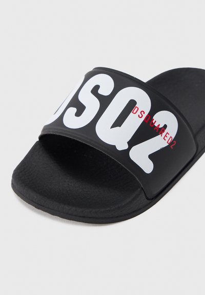 Papuci negri cu o curea lată având inscripția albă îndrăzneață „DSQ2” și un mic accent roșu, fabricați dintr-un material moale, cu talpă texturată.