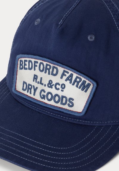 Καπέλο μπέιζμπολ σε ναυτικό μπλε με ορθογώνιο ύφασμα που γράφει "BEDFORD FARM R.L. & Co DRY GOODS" με μπλε κέντημα.