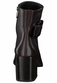 Botín de tobillo de piel marrón con un acabado texturizado, cremallera en el lateral y un acento de hebilla. Presenta un tacón sólido y robusto.