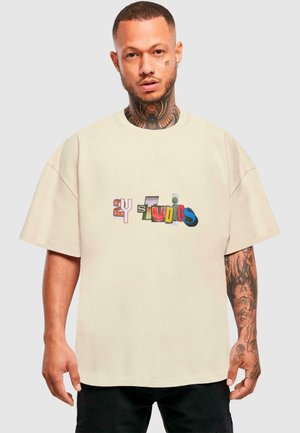 Beige oversized t-shirt with multicolored "2Y Studios" text. Features a round neck and short sleeves, made from soft cotton fabric.