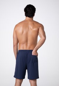 Pantaloni corti in cotone blu navy con vita elasticizzata e tasca laterale. I pantaloni hanno una vestibilità morbida e una texture liscia.