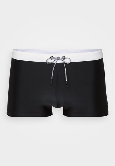 Shorts de bain noirs avec une ceinture élastique blanche, dotés d'un cordon de serrage et d'une texture lisse et soyeuse. Design à jambes courtes avec des accents minimaux.