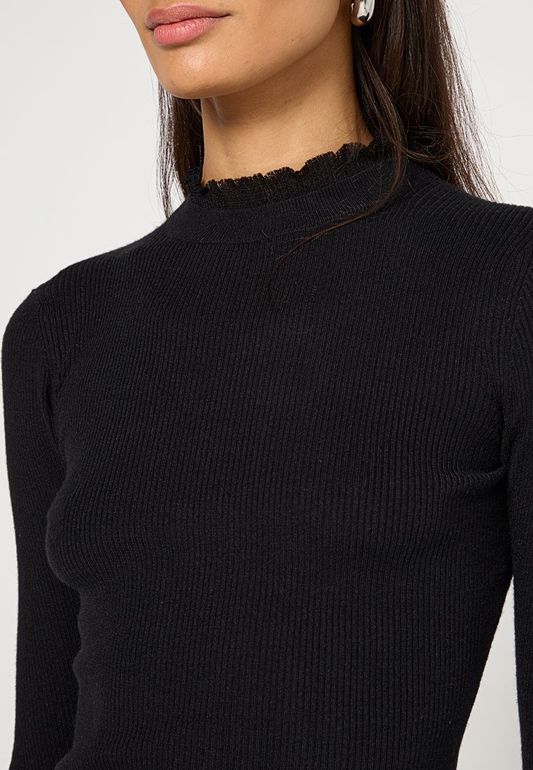 Czarny prążkowany sweter z golfem, z teksturowanym wzorem i falbaniastym dekoltem. Materiał jest miękki, a krój dopasowany.
