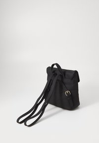 Zwarte gewatteerde tas met een omvouwbare bovenkant en verstelbare schouderbanden. Heeft een gouden gesp-accent en een gladde textielafwerking.