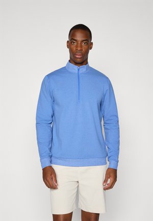 Pullover azzurro chiaro a maniche lunghe con colletto alto e chiusura a mezza zip. Realizzato in tessuto morbido, con una texture liscia e polsini a costine.