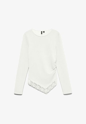 Chemise blanche manches longues avec col rond, ourlet asymétrique avec bordure en dentelle et détails froncés sur le côté.