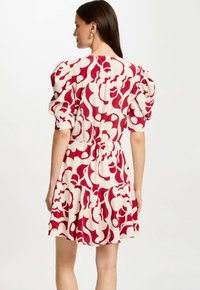 Korte jurk met een witte basis en een rood abstract patroon, met pofmouwen en een elastische taille voor een vloeiende silhouet.