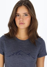 T-shirt biru navy lengan pendek dengan grafis gunung yang halus di dada, terbuat dari kain lembut dan tekstur. Leher bulat.