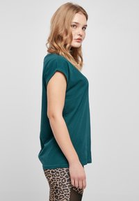 Teal t-shirt med kort ärm, lös passform, mjukt bomullstyg, rund hals, bärs med leopardmönstrade leggings med utskärningar.
