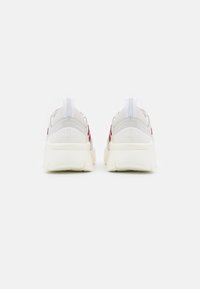 Pari valkoisia ja punaisia Bally-tennareita nähtynä takaa, joissa on paksut pohjat ja vetokahvat yksinkertaisella valkoisella taustalla.