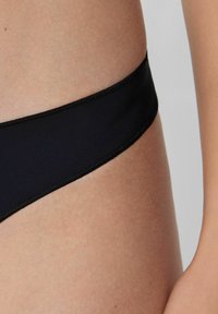 Schwarze Bikinihose aus glattem Stoff. Verfügt über ein niedrig geschnittenes Design mit einem weichen, elastischen Bund und sauberer Nahtverarbeitung.